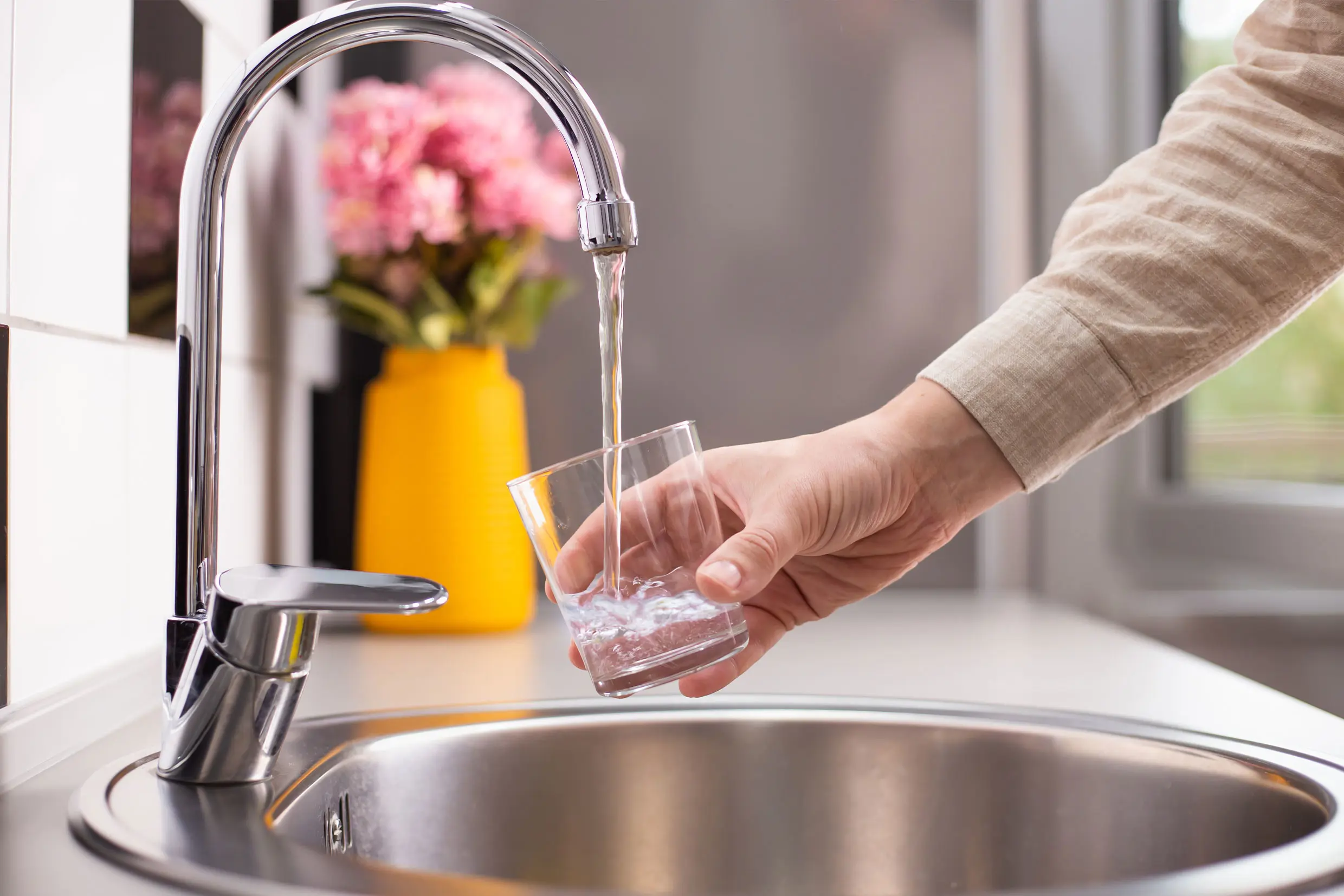 Man filling glass of water at the sink