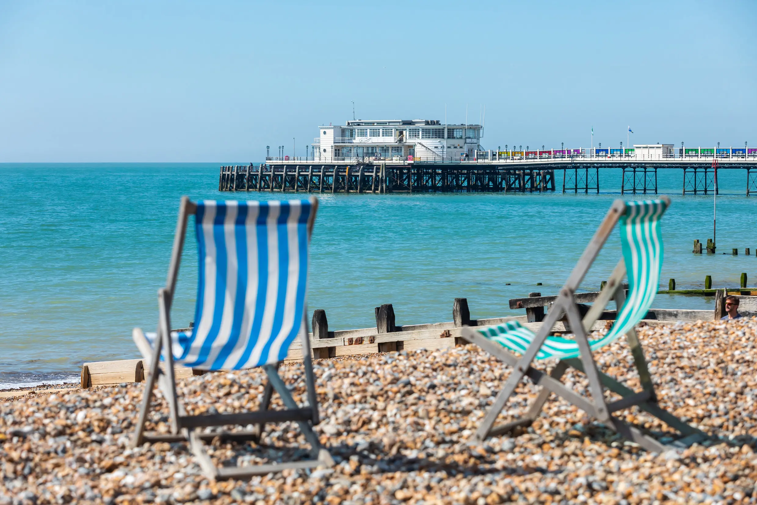 Two deckchairs on Worthing Beach with Worthing Pier in the background