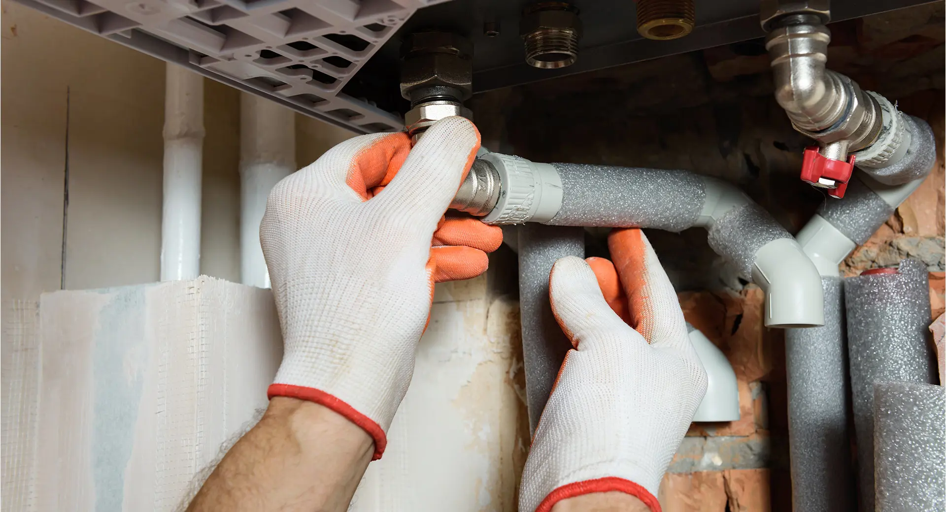 A worker fixing pipes with gloves on