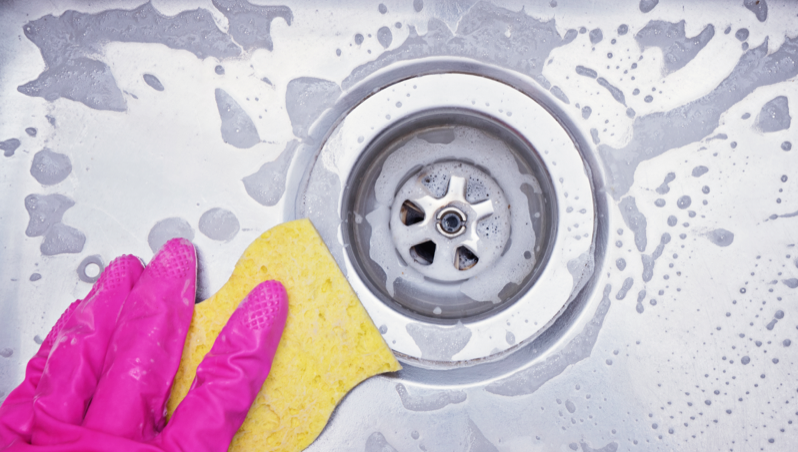 A person washing and cleaning a sink